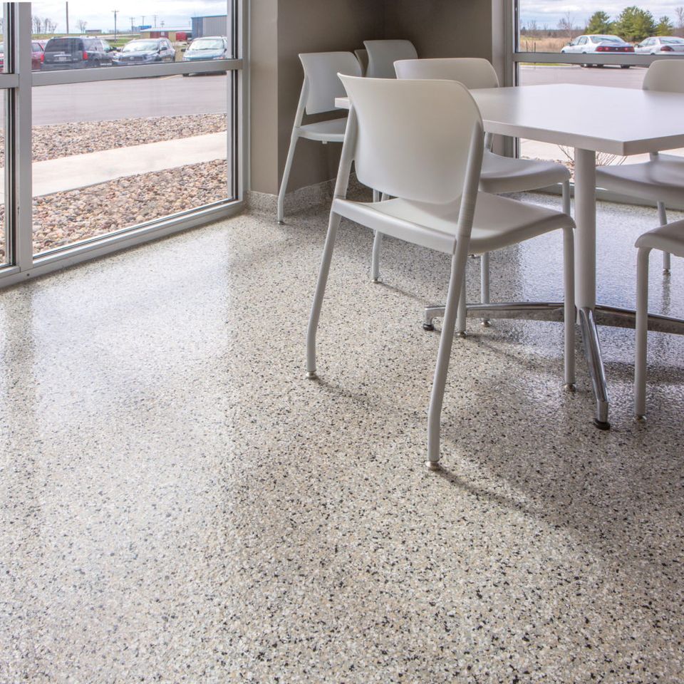 Commercial office with EverStone Flakes flooring, white tables, chairs, and large windows.