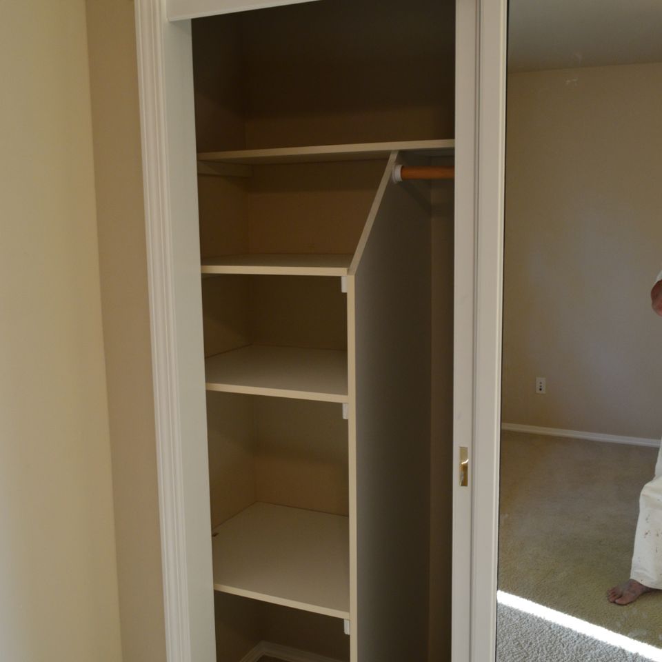 Linen closet with built-in shelving and hanging rod installed in a custom home