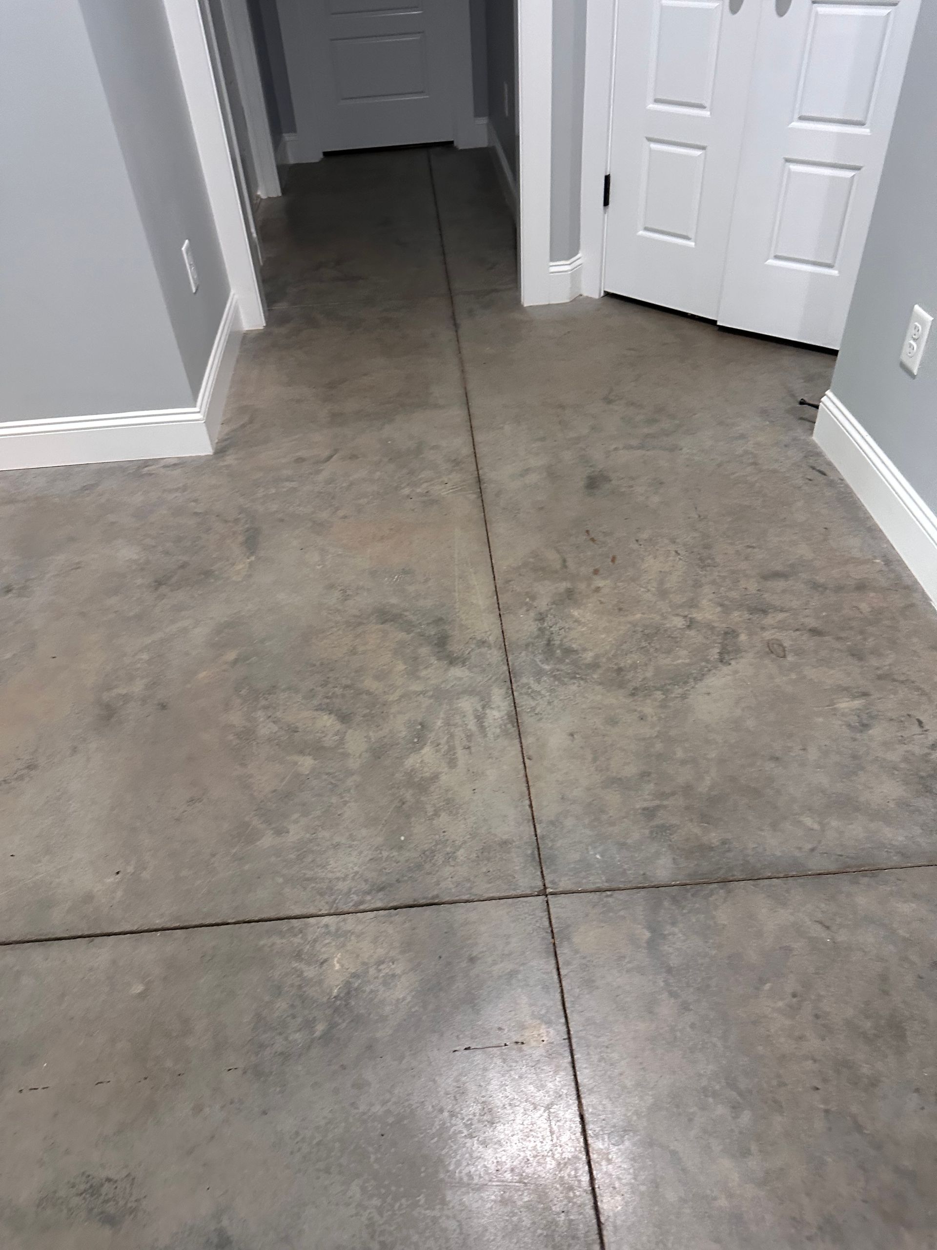 Wide view of finished basement decorative concrete floor with white doors and gray walls