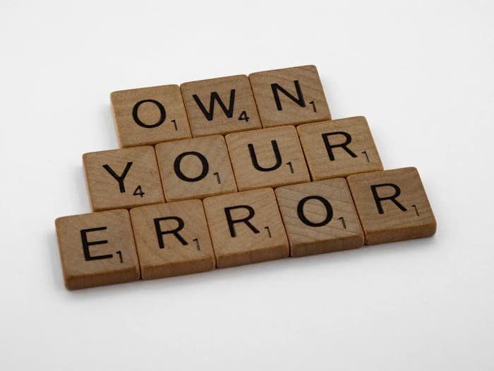 Scrabble pieces spelling out "Own Your Error" 