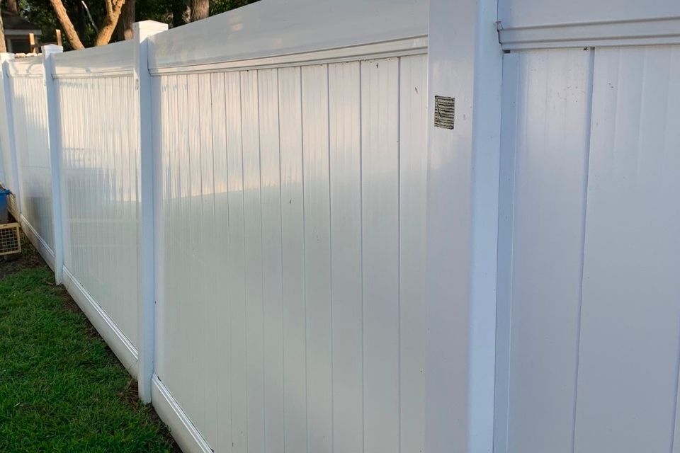 White vinyl privacy fence with decorative post caps installed along backyard in Virginia Beach VA