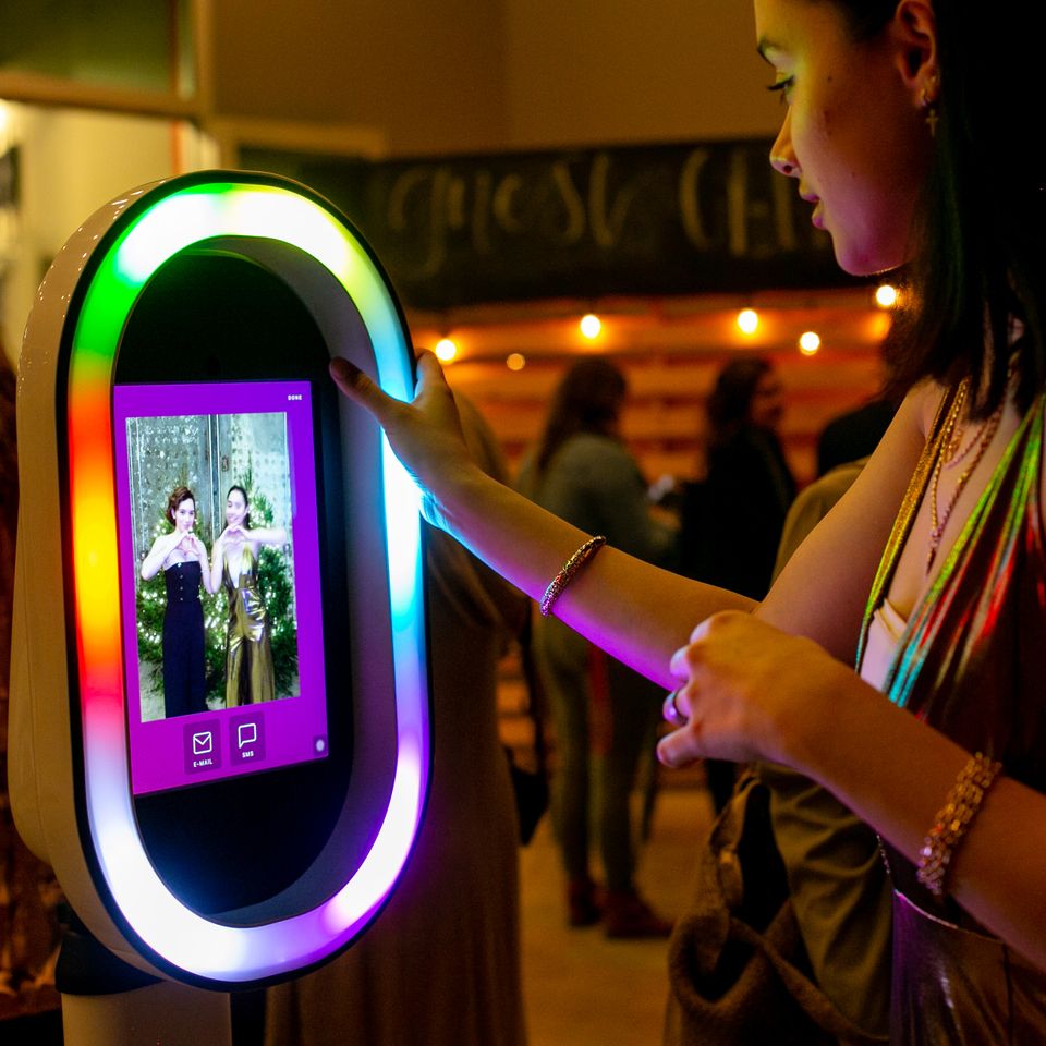 Guest using a colorful LED photo booth at a nighttime event.
