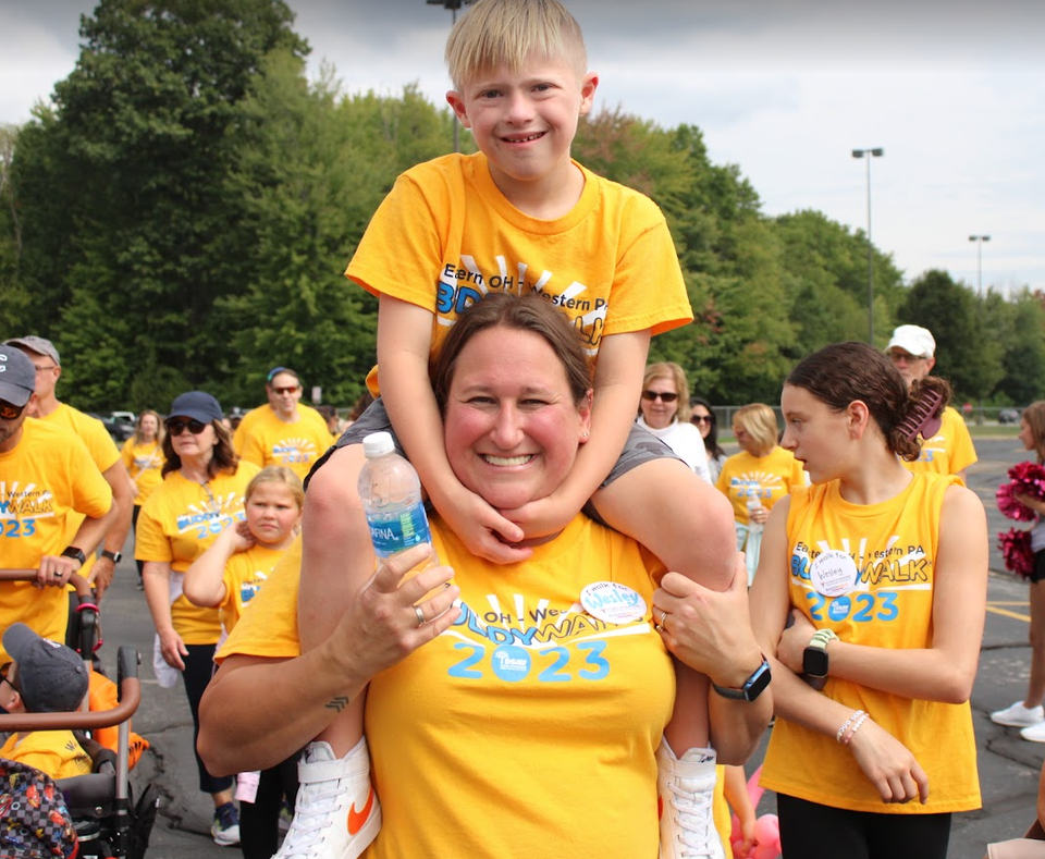 Child riding on an adult's shoulders during the Down Syndrome Association of the Valley Buddy Walk.