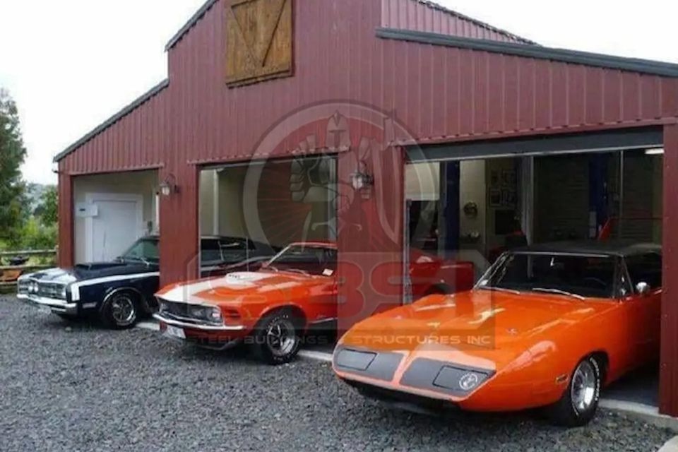 Red steel building with open garage bays and classic cars parked out front with SBSI watermark representing steel garages in Alabama