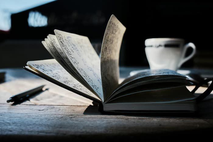 Journal flipping open with a cup of coffee in the background 