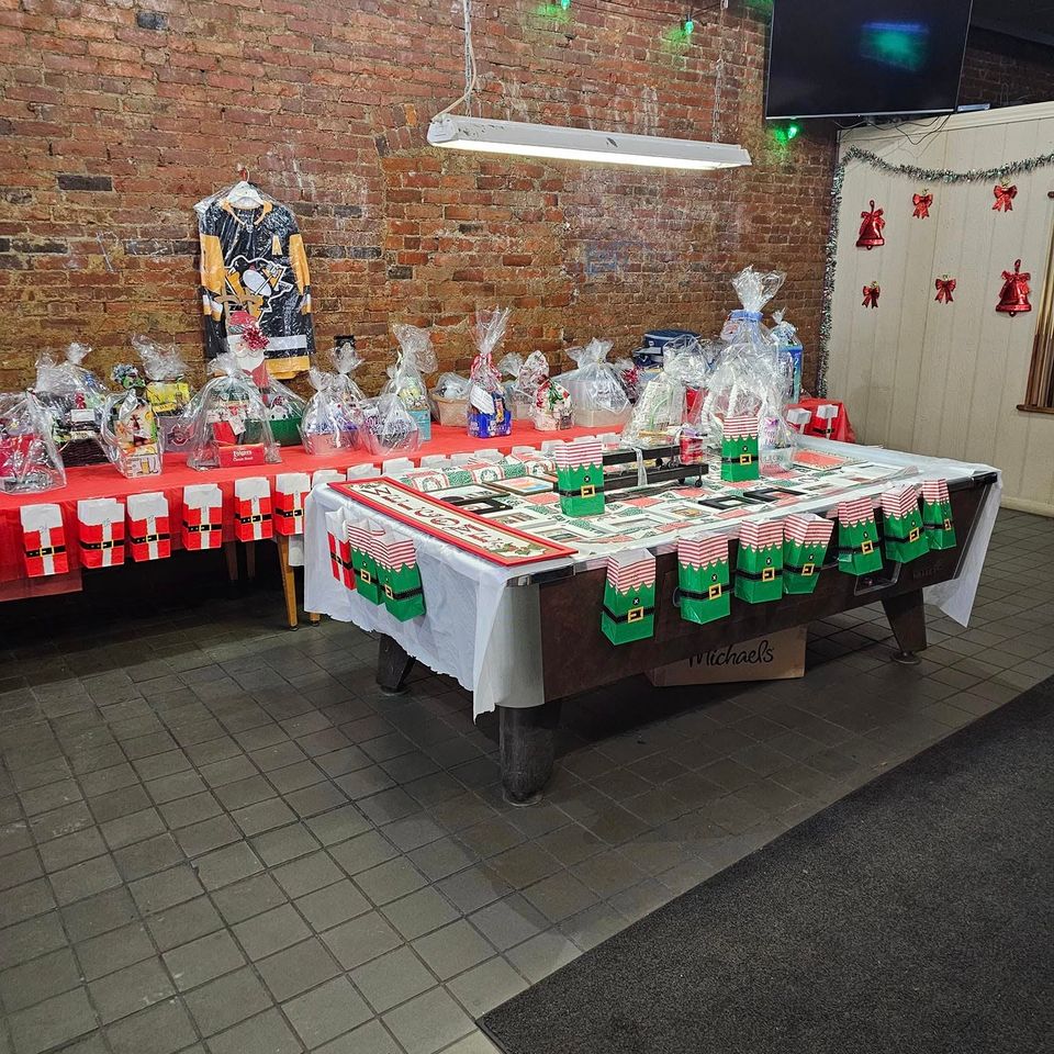 Tables decorated with raffle baskets, prizes, and holiday-themed decorations at an indoor event venue.
