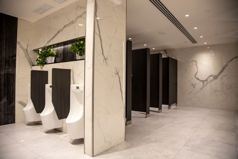 A modern public restroom with black stalls and white urinals