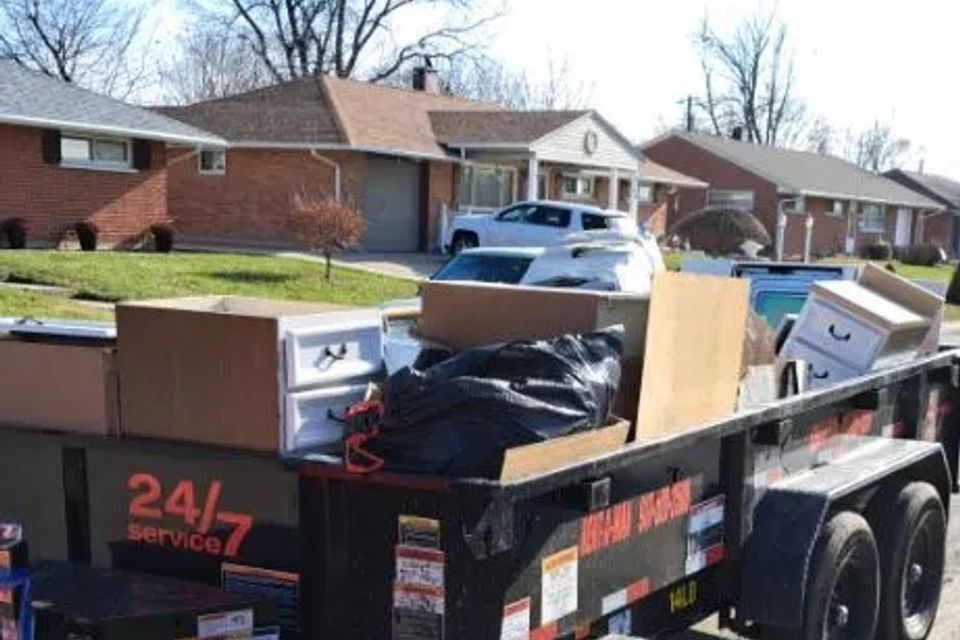 Rent-A-Man Dumpster Rentals trailer filled with furniture, boxes, and household items.