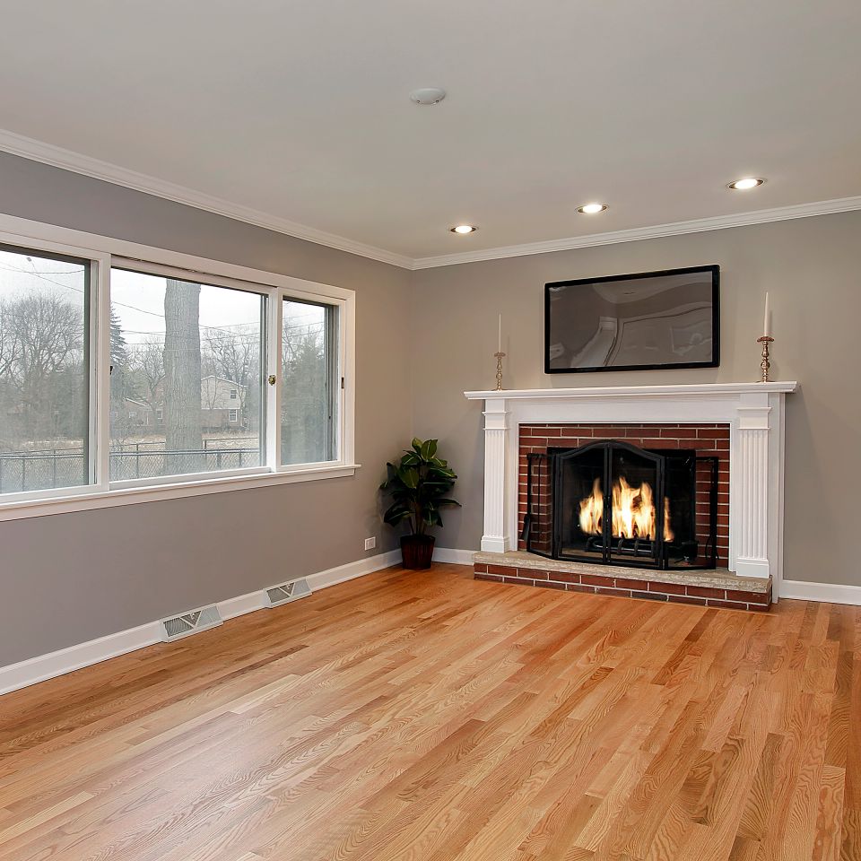 Living room with natural oak hardwood flooring and a white mantel brick fireplace