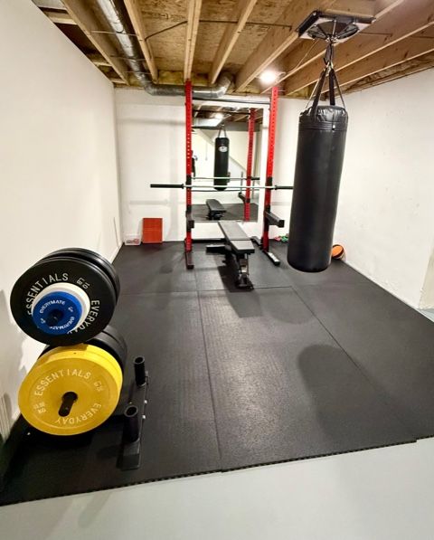 Strength and boxing training area with squat rack, bench, and heavy bag inside an Okemos Michigan facility