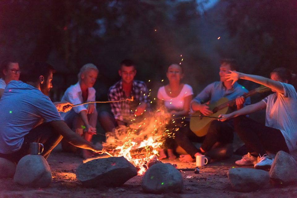 Friends gathered around a campfire at night
