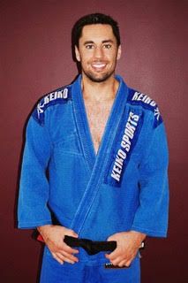 Smiling instructor in a blue gi and black belt at an Okemos MI Brazilian Jiu Jitsu school