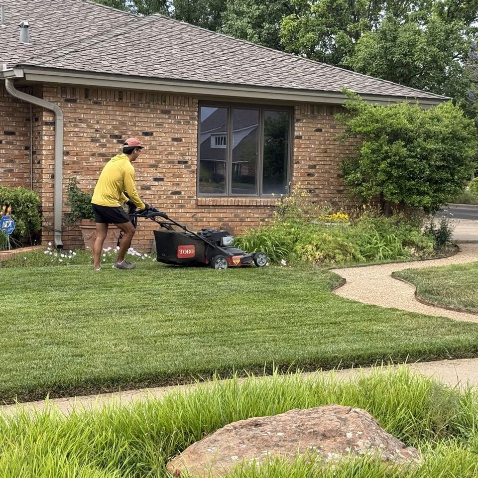 Mowin N Goin crew mowing the front lawn of a brick home in Lubbock
