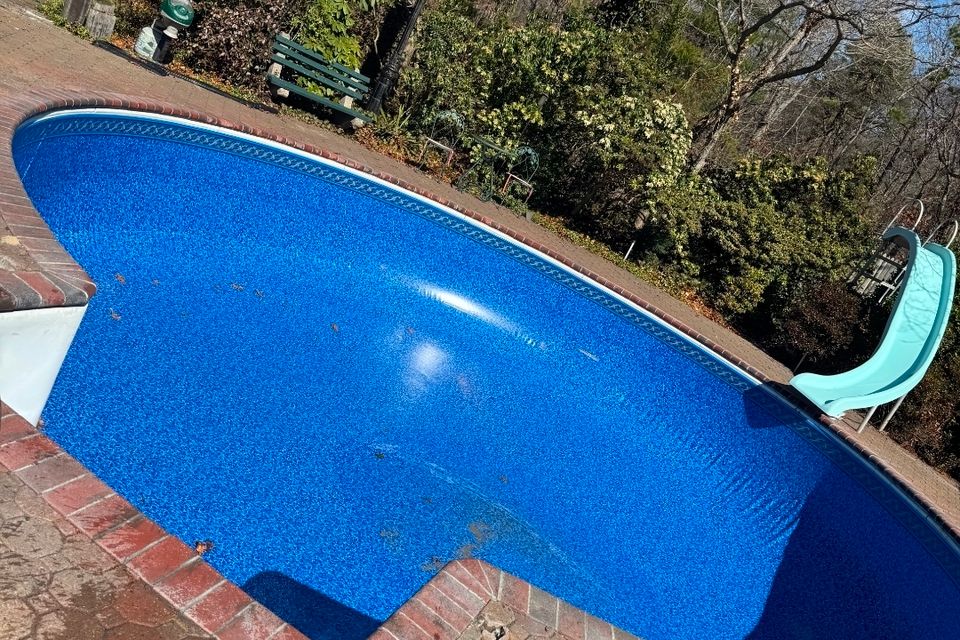 Kidney shaped inground pool with a new blue liner and brick coping installed in Long Island