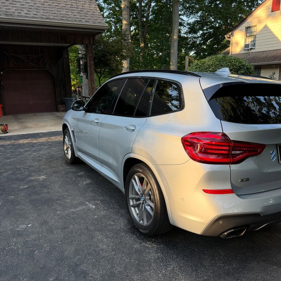 Rear quarter of a silver BMW X3 showing clean paint, taillights, and wheels after exterior cleaning