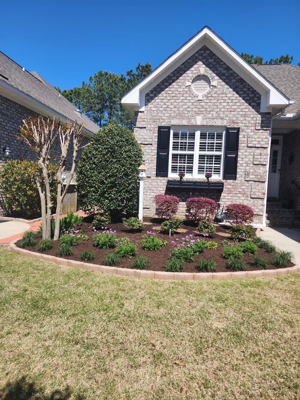 Landscape Design with Plants and Flowers in front of a brick home.