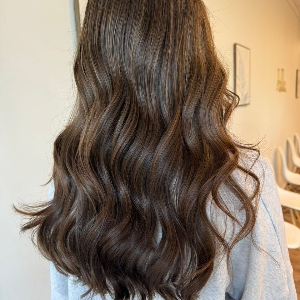 Long wavy rich brown hair with soft caramel dimension after color and styling in Columbiana AL