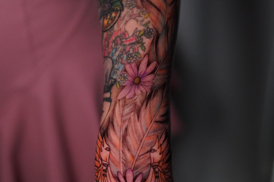 Image of a very colorful and varied tattoo on the top of a woman's forearm