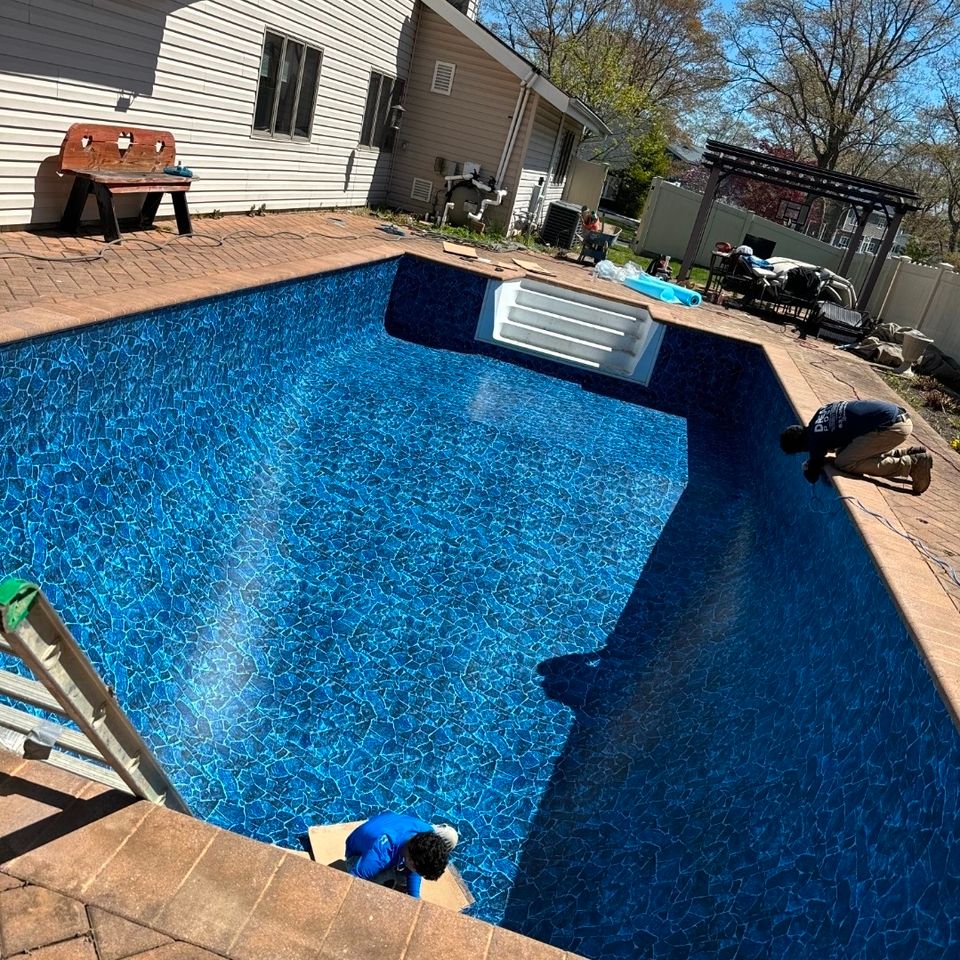 Technicians smoothing a new patterned vinyl liner in an inground pool with step section
