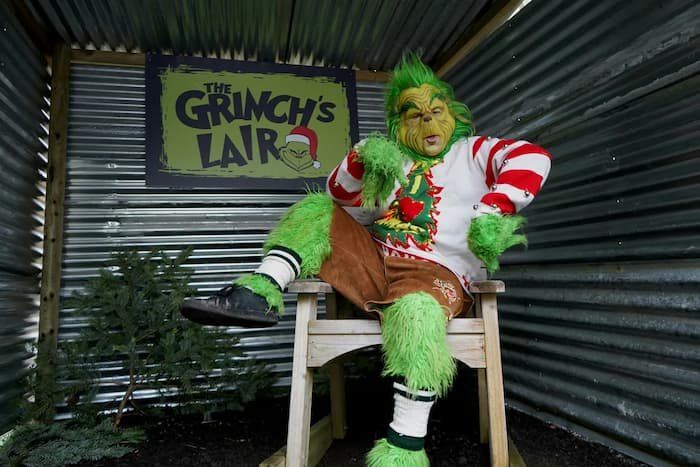 Grinch on a chair inside a semi box car with a sign behind them "The Grinch's Lair." 