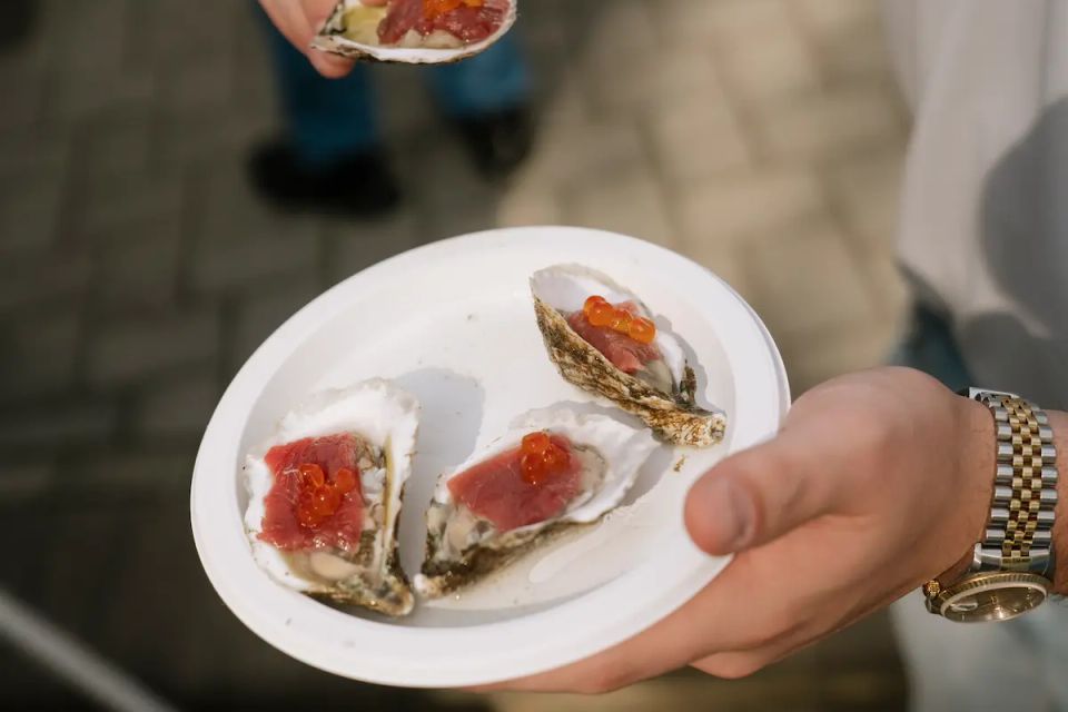 A man holding a clam and other food from a raw bar, provided by Shore2Shore Shucking of Long Island