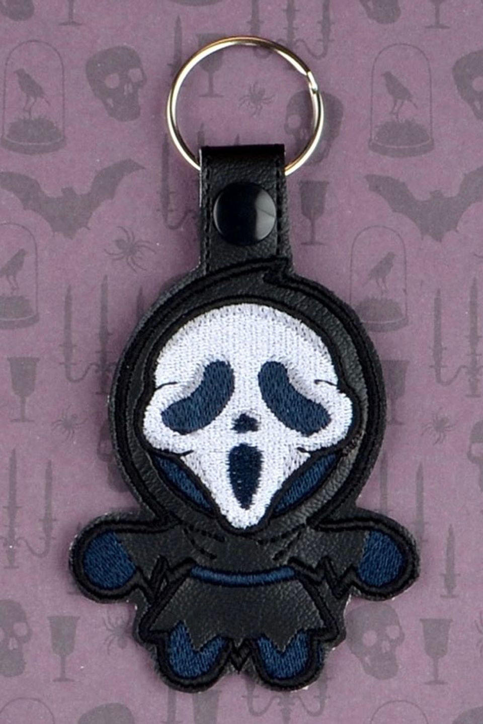 Custom embroidered ghost face-style keychain with a black hood and white mask design.