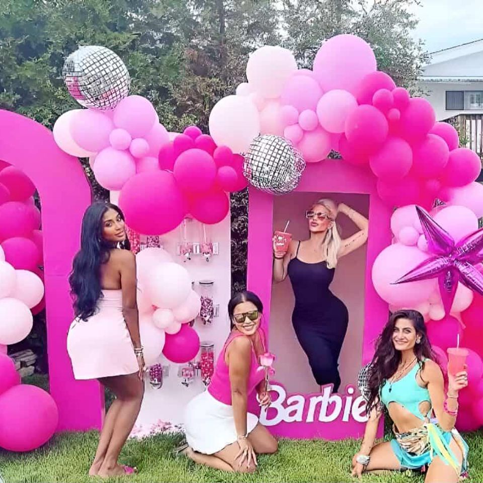 Barbie-themed balloon backdrop in shades of pink with disco balls, star prop, and friends posing for photos at a stylish outdoor event by Aldys Events.