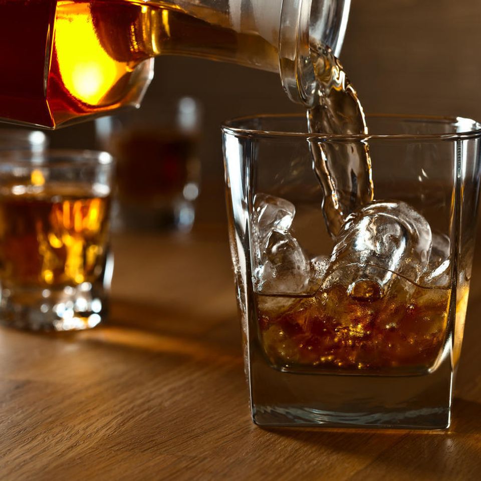 Pouring whiskey into glass with ice istock igorr1