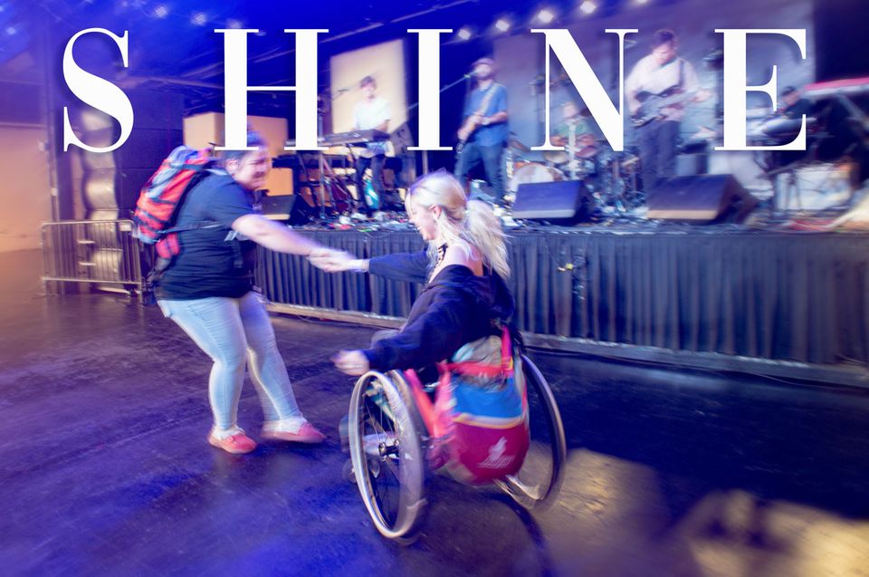 A girl in a wheelchair dancing with another girl at Shine Music Festival 2023