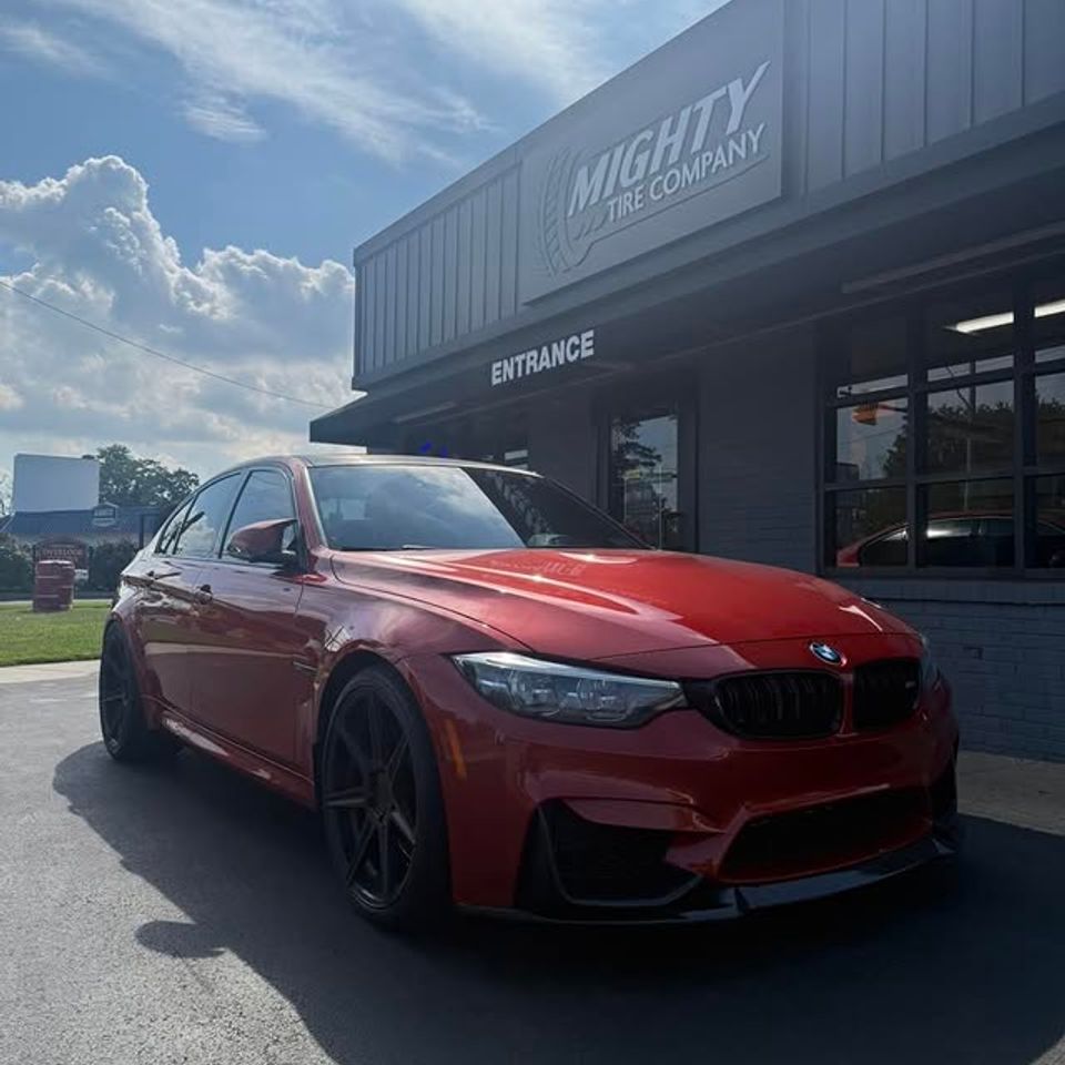 Red BMW sedan parked outside Mighty Tire Company storefront after tire service in Claymont DE