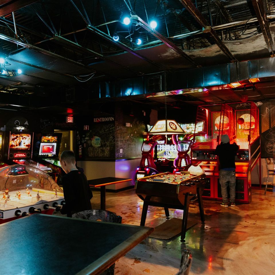 Wide view of arcade games with people spread around playing some of them