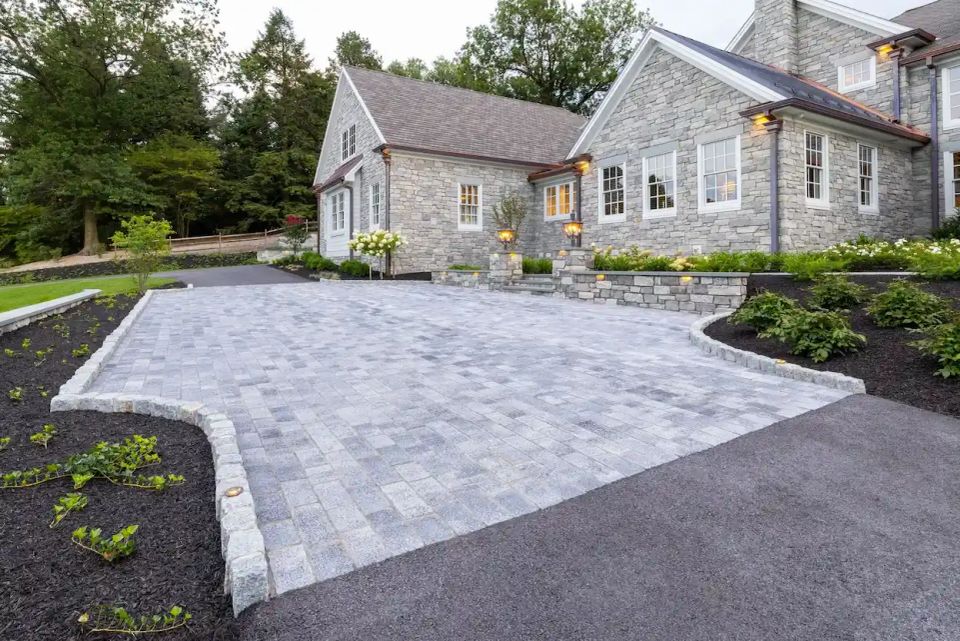 Luxury paver driveway with retaining walls, landscape lighting, and custom stonework at a high-end home in Charlotte NC