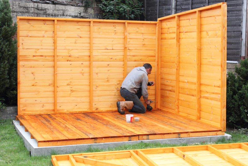 A man building a wooden shed outside