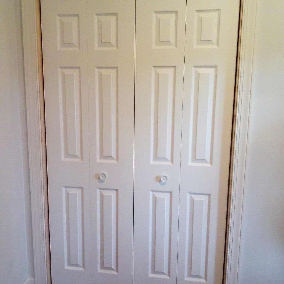White six panel bifold closet doors with trim installed in a Chagrin Falls bedroom