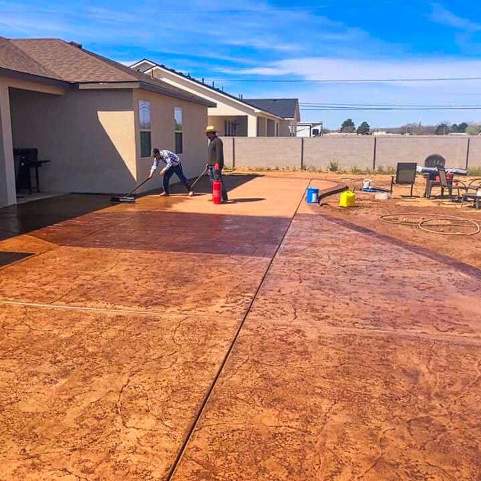 Professional masonry team detailing and cleaning a sand-colored cement surface to reveal the decorative finish on a custom backyard patio project by Roseville Concrete Solutions.