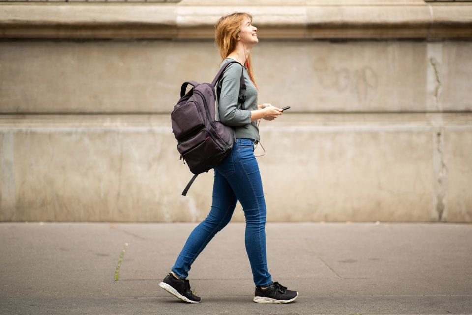 Woman with a backpack walking city sidewalk with steady energy after Alleviate therapy in Palm Beach County