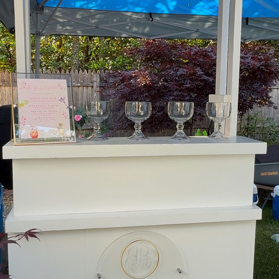 White mobile bar cart with cocktail menu and glassware set up for bartending service in the Hamptons NY
