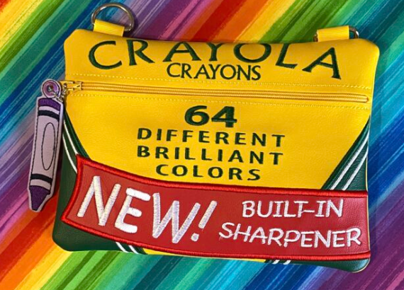 Custom embroidered zipper pouch designed to resemble a vintage crayon box with bright colors and crayon-themed details.