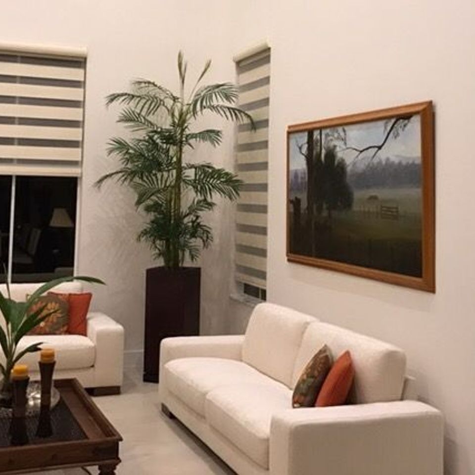 Zebra window shades in a tall, modern living room with white furniture and high ceilings