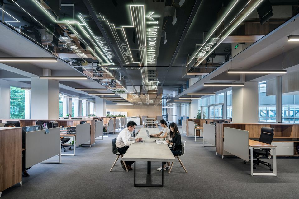 Interior office building cubicles and people working at desks