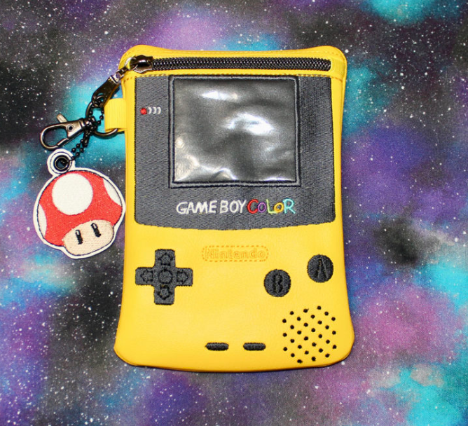 Custom embroidered yellow zipper pouch styled like a retro handheld gaming console with screen details and mushroom charm.