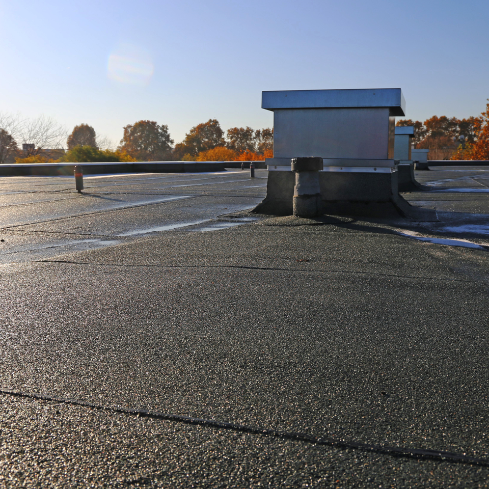 Commercial flat roof with roofing system, rooftop vents, and HVAC curbs installed by E & D Roofing, Inc.