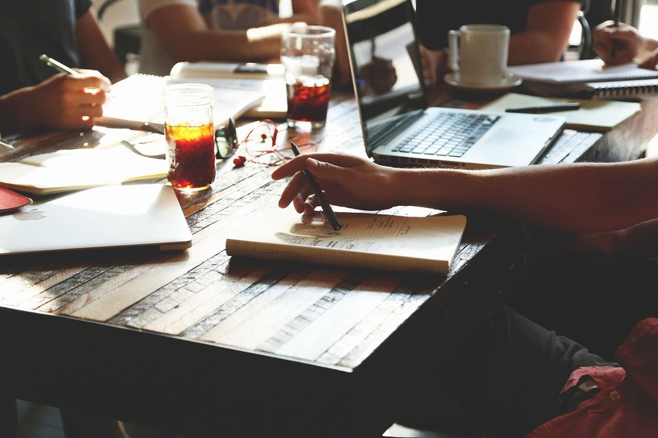 people working at a table with laptops and papers