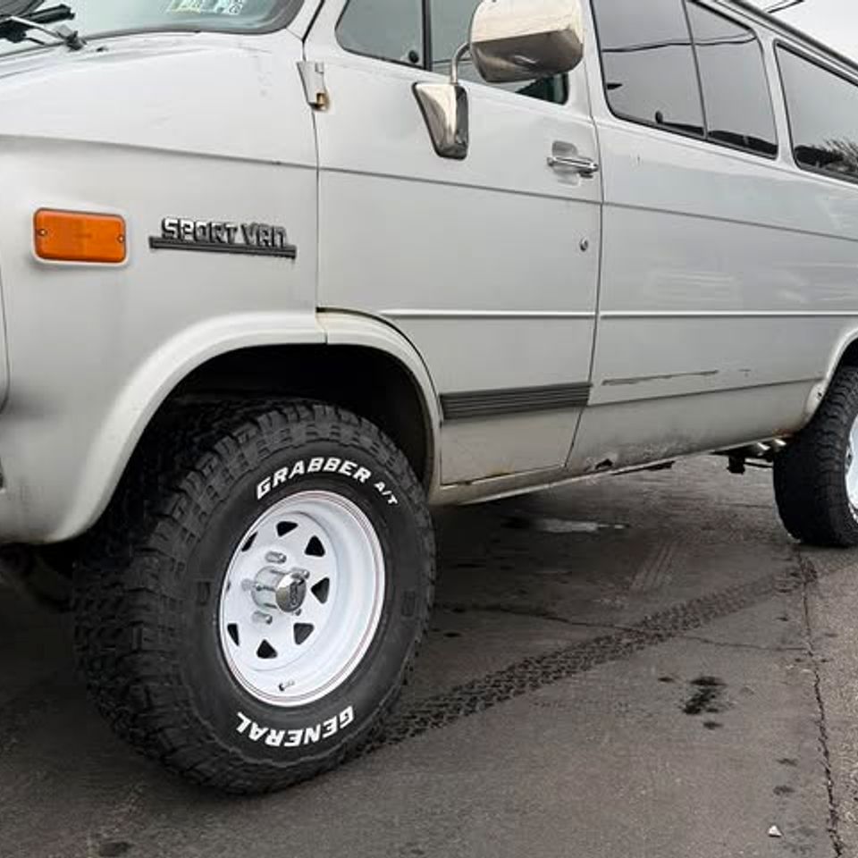 White Chevy Sport Van with new General Grabber off-road tires and white wheels in Claymont DE