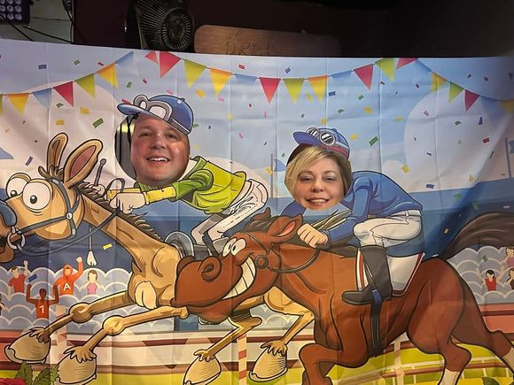 Two guests posing in a Kentucky Derby horse racing photo booth at JR's.