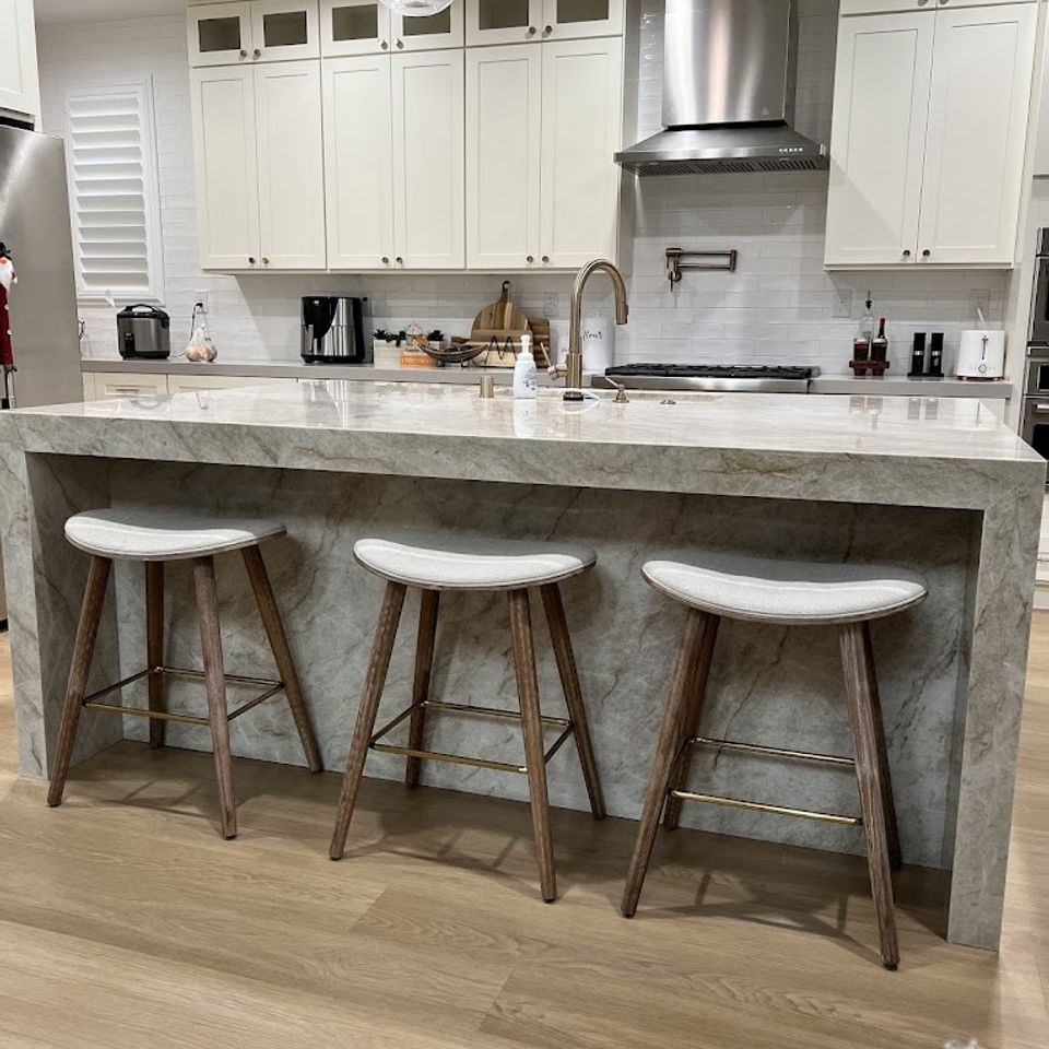 High-end kitchen featuring a massive grey veined quartz island with a custom mitered waterfall edge and matching stone-cladded base—Expert stone fabrication and professional installation for Sacramento luxury homes by LuXe Design Tile and Granite inc..