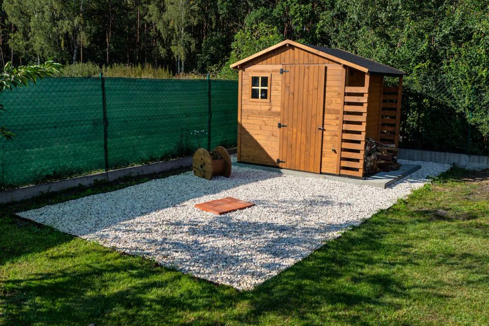 A wooden garden shed standing on a concrete foundation in a garden