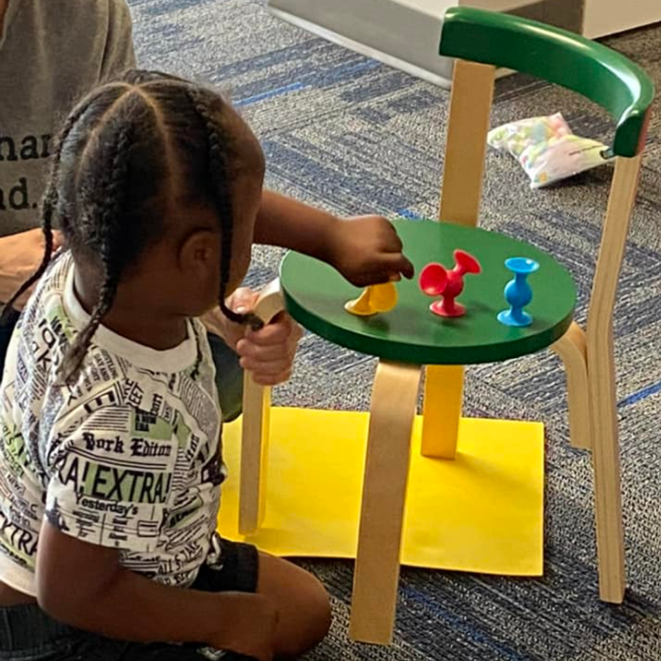 Young child participating in a hands-on learning activity during a Down Syndrome Association of the Valley early childhood program.