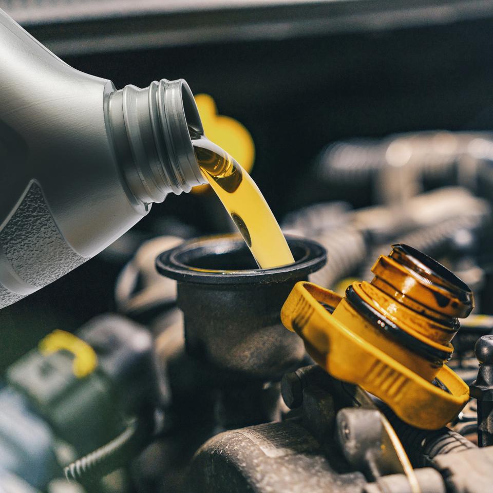 Engine oil being poured into a vehicle during a professional oil change service.
