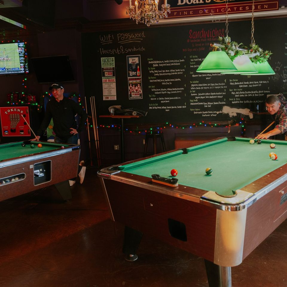 Two groups playing pool on two different pool tables